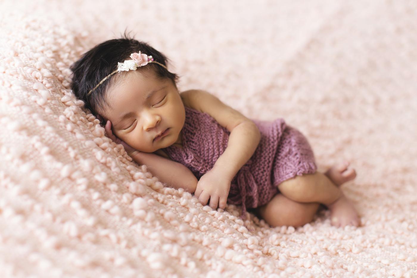 Baby girl. Purple dress. Pink blanket. Sleeping. Close up. 